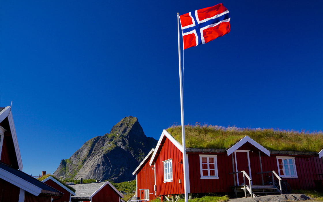 Norwegische Flagge vor roten Häusern.