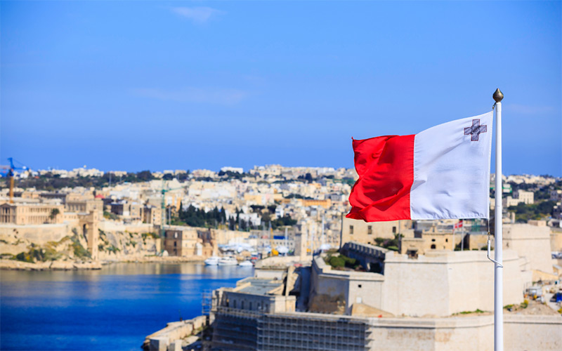 Blick auf Malta. Im Vordergrund die maltesische Flagge